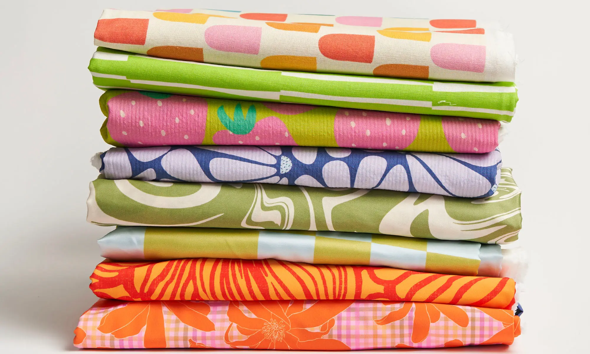 Stack of colorfully printed summer apparel fabrics.
